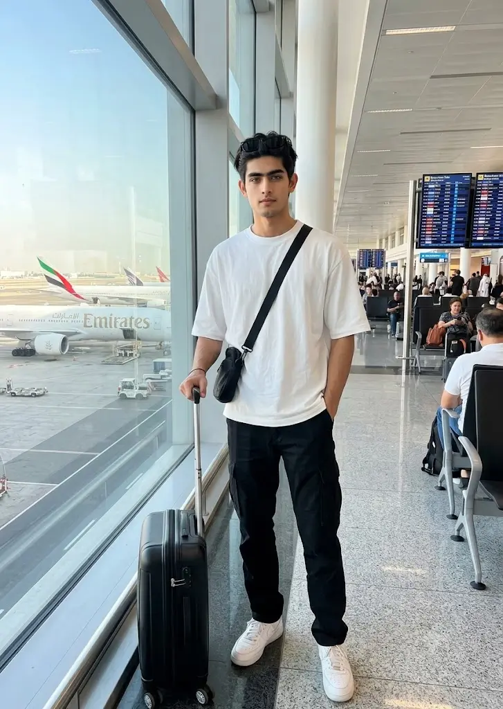 Realistic Gemini AI airport terminal travel portrait of a stylish boy with suitcase and modern airport background.